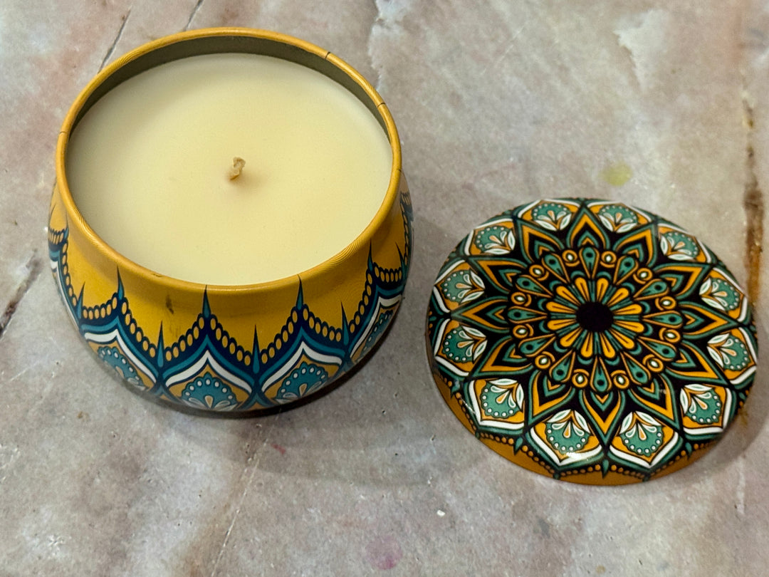 Decorative candle in a yellow container with a mandala design lid.