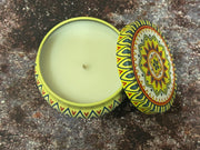 Decorative candle in a tin with a colorful lid on a textured surface
