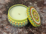 Decorative candle in a tin with a colorful lid on a textured surface