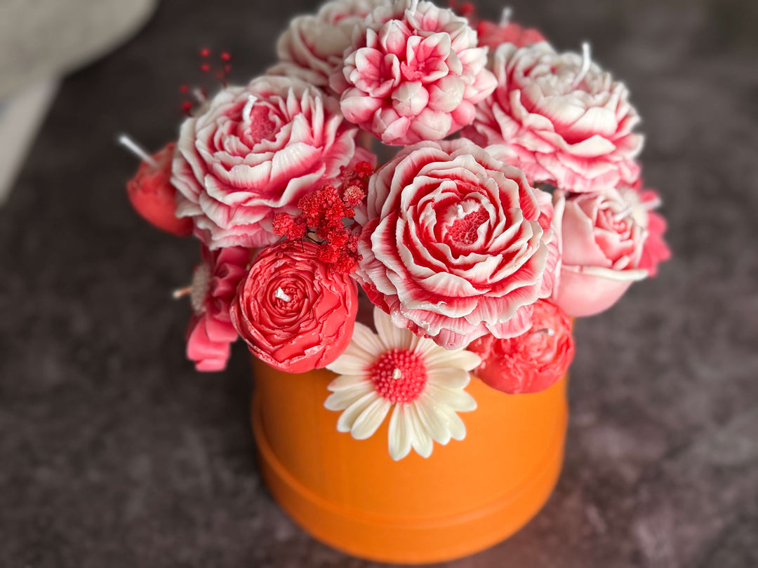 Bouquet of White and red flowers in an orange vase on a dark surface