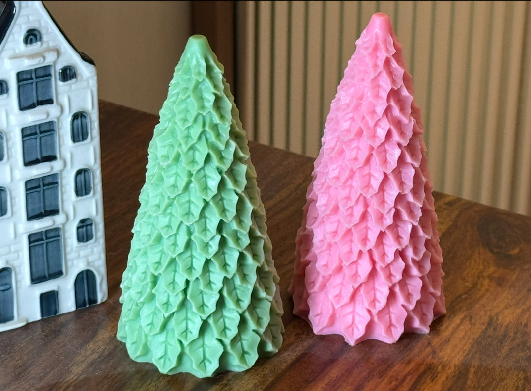 Two textured Christmas tree-shaped candles, one green and one pink for festivities