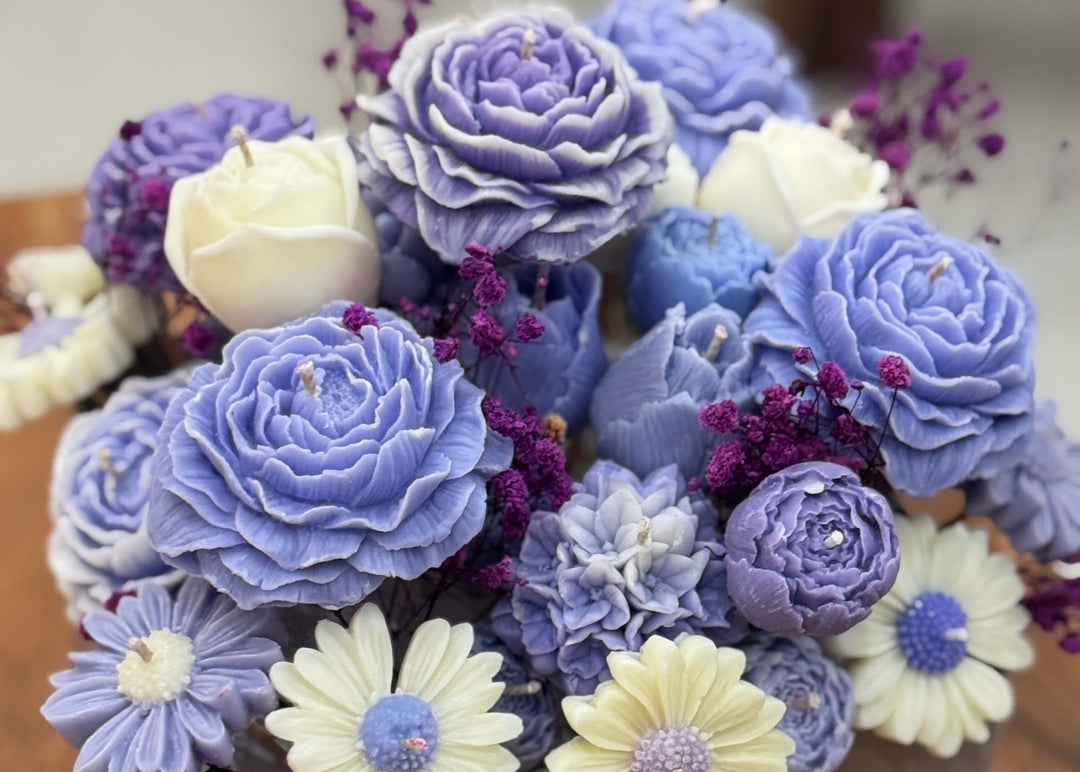 Decorative flowers made of soy wax in hues of purple, blue, and white.
