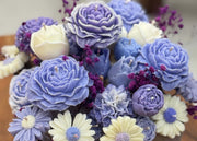 Decorative flowers made of soy wax in hues of purple, blue, and white.