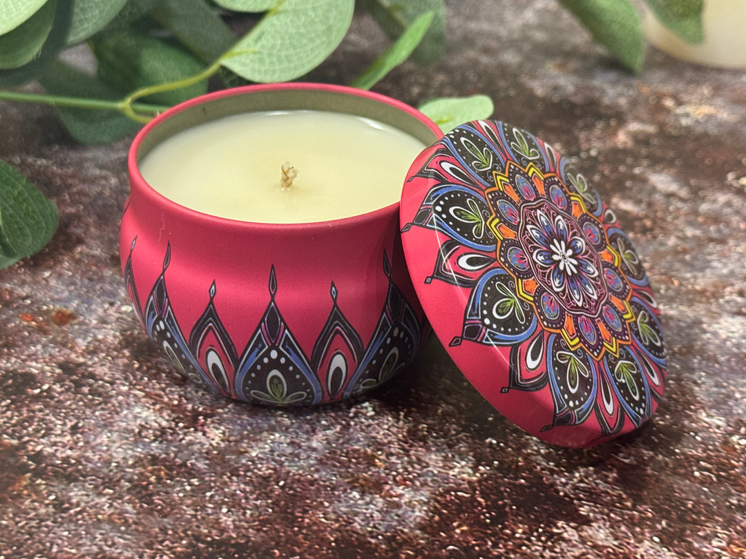 Decorative candle in a red tin with mandala design.